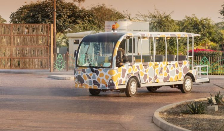 Tourist bus at Dubai Safari Park surrounded by lush greenery and wildlife enclosures.